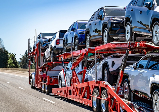 Car transport and carrier finance options arranged to fund a large red double-decker car carrier trailer loaded with new SUVs on an open highway