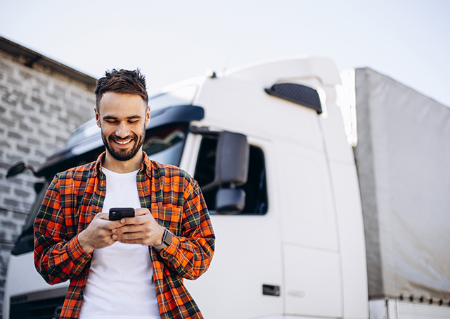 Trucker standing next to his white truck, speaking on the phone.