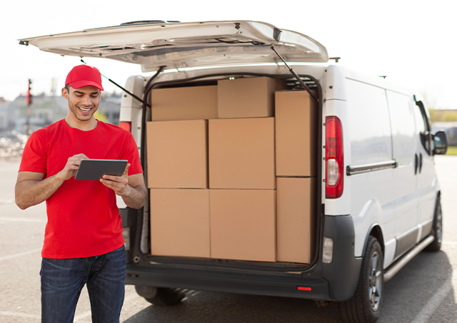 Easy commercial van finance with quick competitive loan options for a smiling young delivery man in uniform standing by his vehicle with parcel boxes