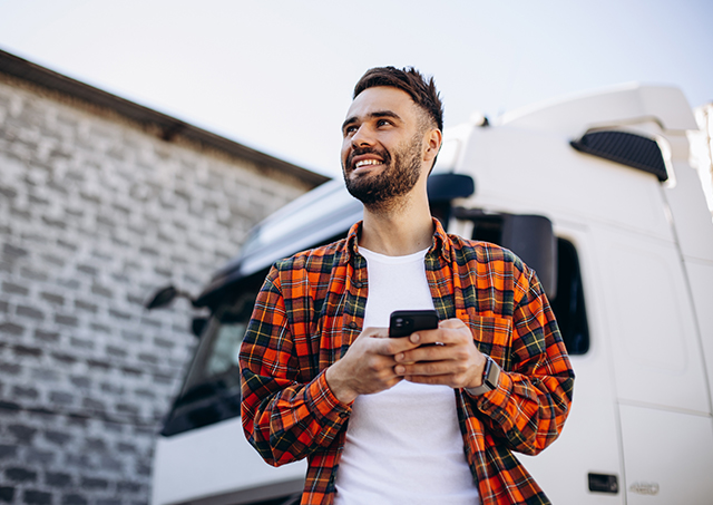 Commercial Hire Purchase | Check your eligibility with Easy Truck Finance, like this truck driver using a phone while standing beside a white lorry