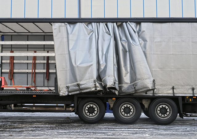 Commercial transport trailer loans utilised to purchase a heavy-duty freight vehicle with a silver curtain side pulled open