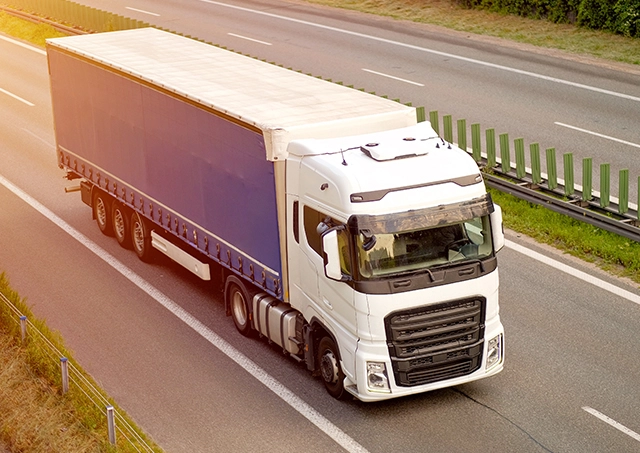 Curtainsider Truck Finance options used to fund a white prime mover pulling a blue trailer on an open highway