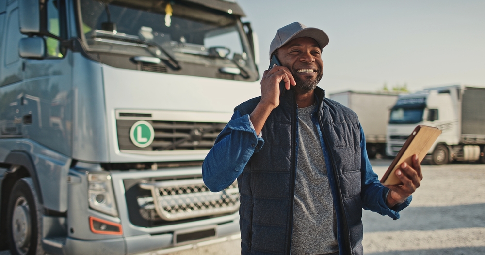 Commercial truck financing Australia wide with Easy Truck Finance for a transportation worker talking on the phone and smiling with a tablet in hand