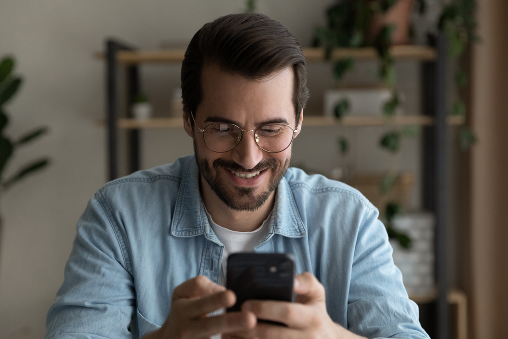 Fast commercial truck loans and low rates for a smiling man in glasses using a smartphone