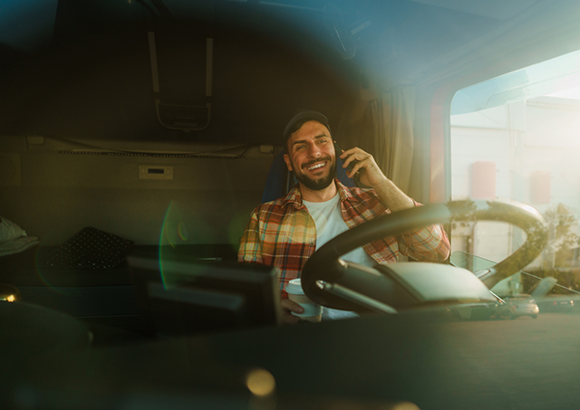 Personalised truck lease solutions with Easy Finance for a truck driver sitting in the cabin talking on the phone while holding a coffee cup